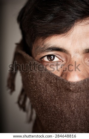 Close up of an covered face by scarf of Indian farmer isolated on gray background