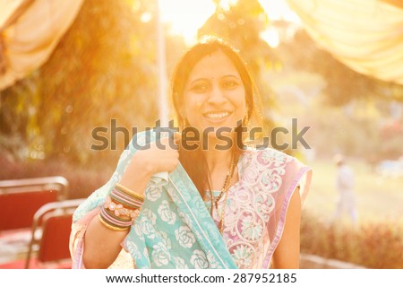 Indian happy woman in sari looking at camera in blue and pink saree