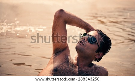 Indian happy man swimming and relaxing in ocean of an Island with sunglasses