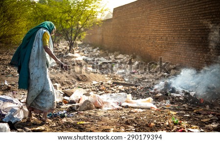 Pollution and poverty. Indian old female searching food in urban industrial garbage on 13 Feb, 2012. Kanpur, India