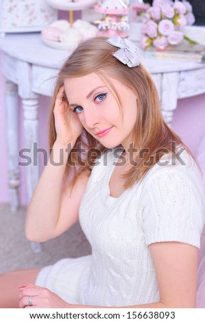 Pretty blonde girl with knitted dress, little bow in hair indoors
