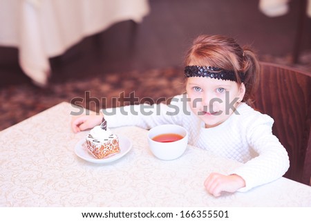 Cute girl sitting with cup of tea in restaurant