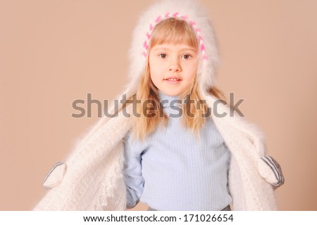 Portrait of smiling baby girl wearing winter clothes in studio at beige background