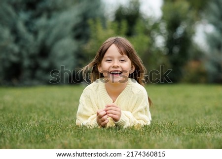 Similar – Image, Stock Photo 4 year old blonde girl with a brightly colored striped sweater sits at a wooden table and draws with a purple pencil on a piece of white paper