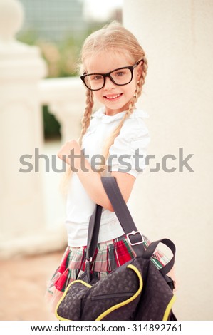Happy kid girl holding school bag outdoors. Looking at camera. Happiness. Back to school. Childhood.