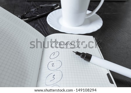 Note to do, cup, glasses and pen on black table