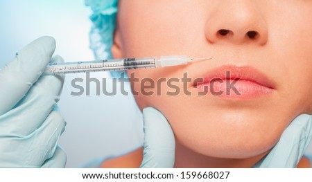 Doctor makes a cosmetic injection in the upper lip