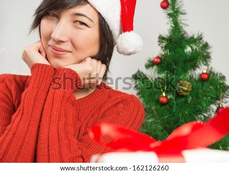 Young woman in santa hat smiling on the background of Christmas tree