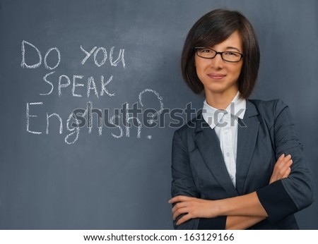 Young woman in a suit standing near the blackboard, English lesson