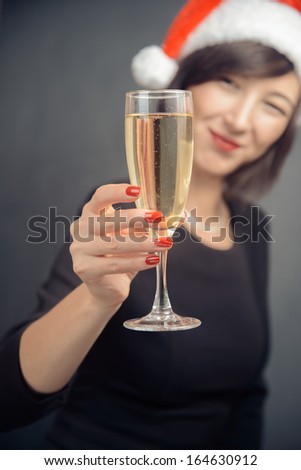 Happy woman in santa hat is giving glass with champagne