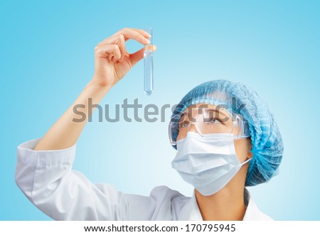 Female lab technician looks at a test tube of clear liquid