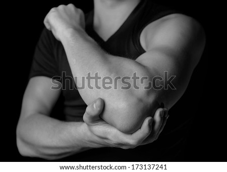 Man holds his the elbow joint, acute pain in the elbow, black and white image