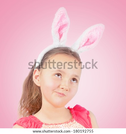 Portrait of little pensive girl dressed in Easter bunny ears on a pink background
