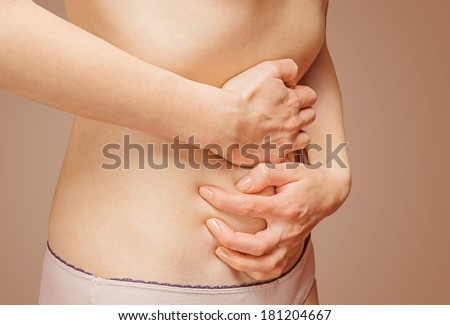 Unrecognizable woman holds her abdomen, side view, abdominal or menstrual pain