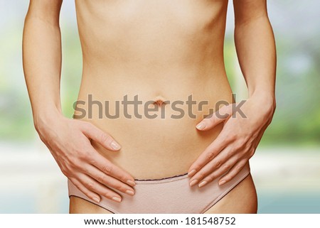 Female slim belly, hands on the abdomen, face is not visible