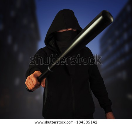 Dangerous man in the mask with baseball bat ready for fight in the night city