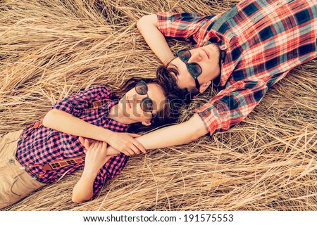 Hipster style couple in love is lying on meadow