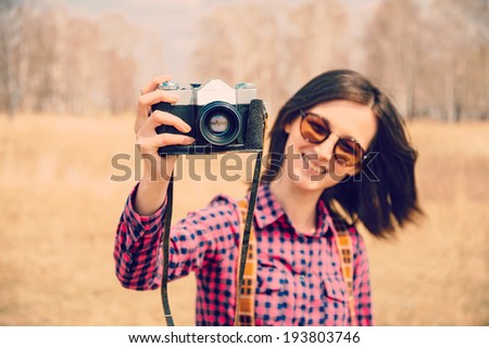 Happy woman takes photographs with old photo camera outdoor