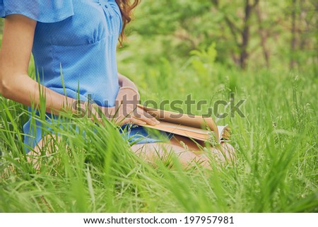 Unrecognizable woman reads a book in park in summer