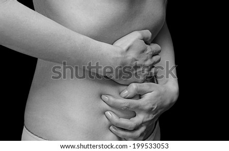Unrecognizable woman holds her abdomen, side view, abdominal or menstrual pain, monochrome image