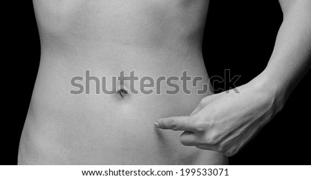 Woman points to a thin abdomen, space for text, face is not visible, monochrome image