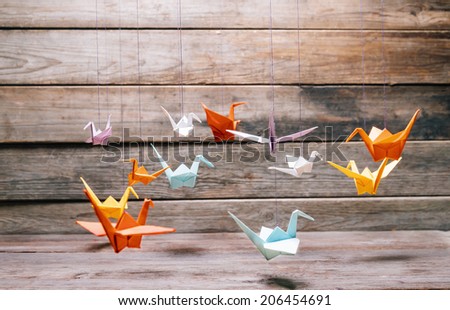 Colorful origami paper cranes on wooden background