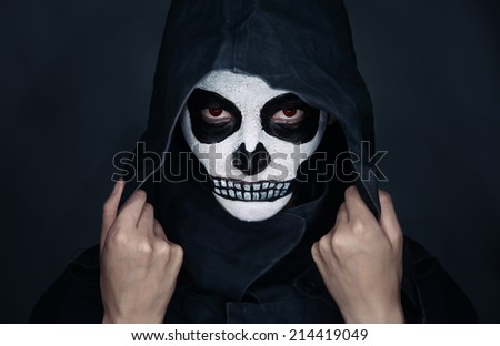 Woman with skull makeup in hood looks at camera, Halloween face art
