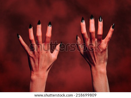 Red hands of the devil on background of fire. Halloween or horror theme