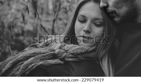 Smiling couple in love rests in park, man embraces a woman. Black and white image