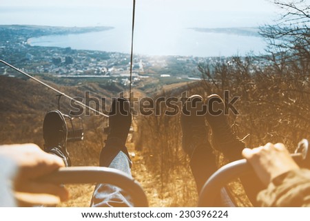 Couple sitting in lift chair of cableway, view of legs on background of sea. Low contrast effect