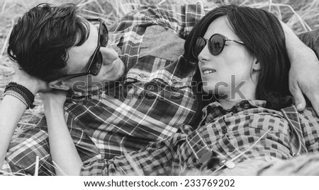Young hipster style couple is talking to each other outdoor. With film grain effect. Black-white photo.