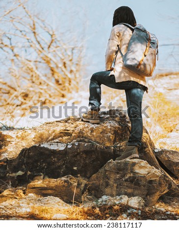 Hiker woman with backpack go up on rock, rear view. Hiking and recreation theme