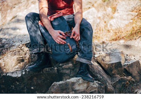 Unrecognizable hiker man opening his backpack on nature. Hiking and recreation theme