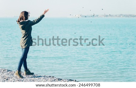 Young beautiful woman walking on the beach and she throwing stones in the sea