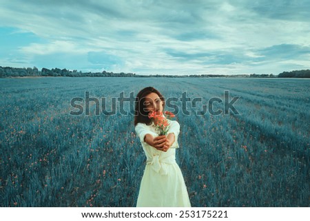 Beautiful young woman holding bouquet of red wildflowers on summer fantasy meadow. Focus on face woman.