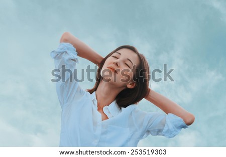 Beautiful young woman enjoying a nice day on a background of sky