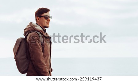 Young handsome man standing on coastline and enjoying a nice day