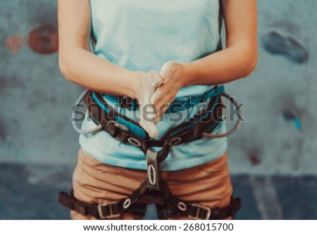 Climber woman coating her hands in powder chalk magnesium and preparing to climb indoor, close-up