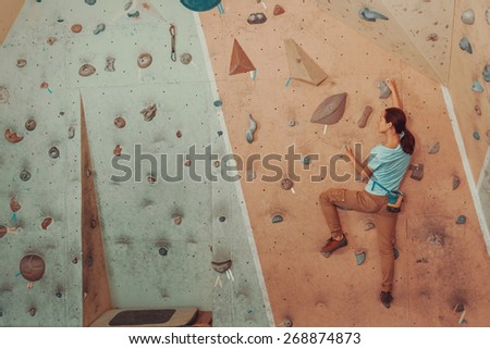 Free climber young woman climbing artificial boulder in gym