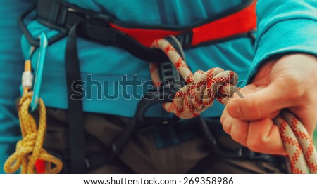 Rock climber wearing safety harness, rope and climbing equipment, close-up image