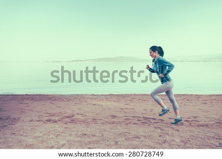 Young woman running on sand beach near the sea in summer in the morning. Concept of sport and healthy lifestyle. Space for text in the left part of image. Image with instagram filter