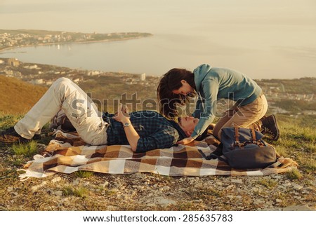 Loving couple resting on peak of mountain above the bay in summer