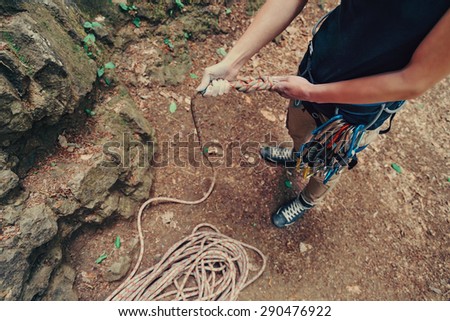 Climber woman wearing in safety harness with equipment holding rope and preparing to climb, top view