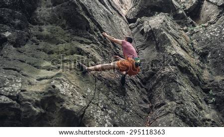 Free climber man climbing on stone rock outdoor in summer, bouldering