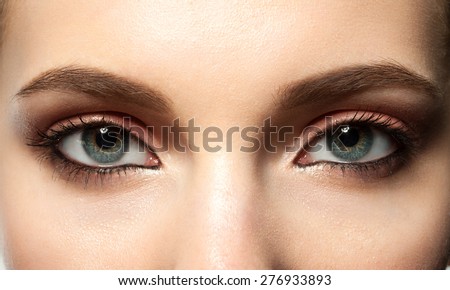 Open female blue eye with makeup with brown eyebrows and black lashes