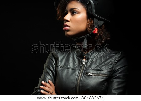 Black girl in a motorcycle helmet and leather jacket on a black background