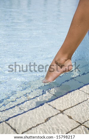 Feet step into the clear water swimming pool