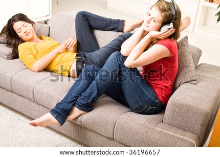 Beautiful blondie brown teenager girls listen music at home on sofa