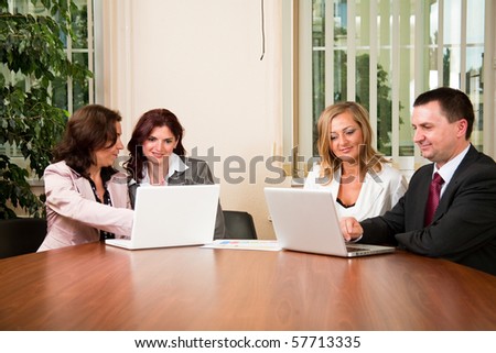 Group of four business people working on laptop at meeting