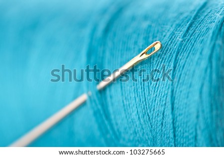 silver needle with golden head inserted into blue thread